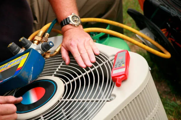 Technician checking refrigerant pressures on an aircon outdoor condenser