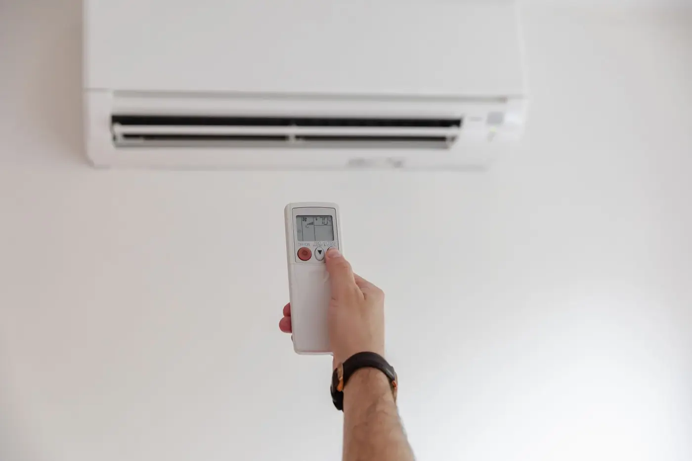 Hand pointing a remote at a wall split unit fitted during an aircon installation in Fourways