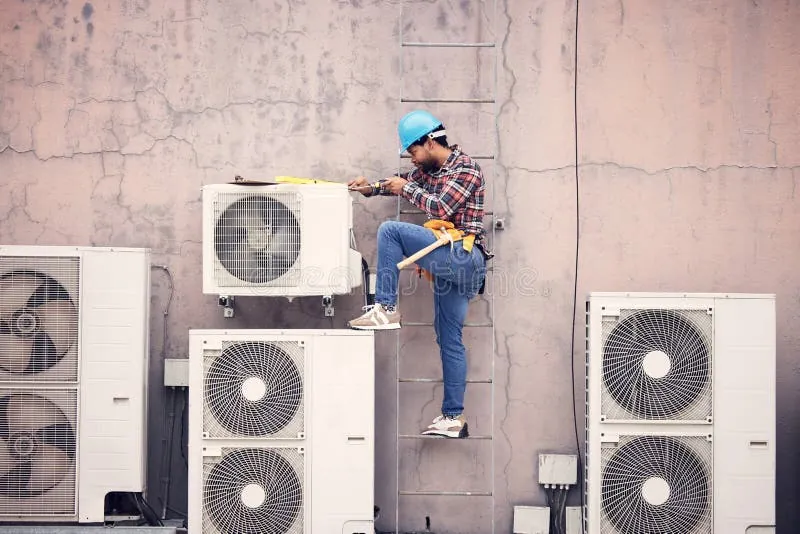 Technician working between several outdoor units mounted on a commercial building wall